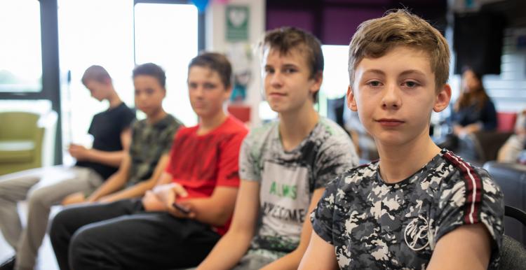 Five young boy sitting in a row smiling at the camera