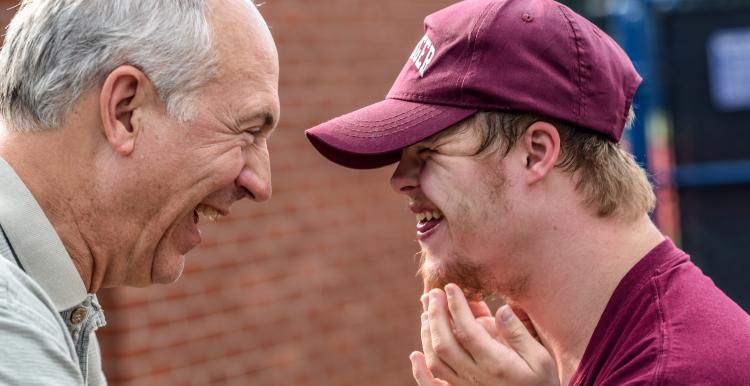 Young man with learning disabilities smiling at an older man