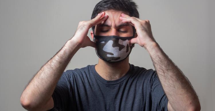 Person wearing face mask and holding head