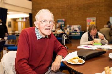 Man sitting at a table with a slice of cake smiling at the camera