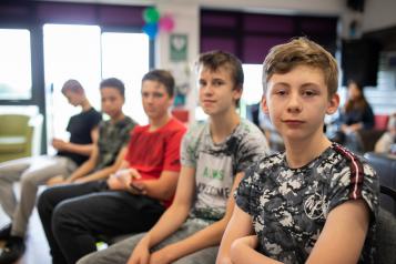 Five young boy sitting in a row smiling at the camera