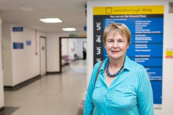 Woman standing in a hospital corridor in front of a sign