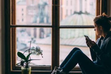 Young women sitting in bay window looking out on on the world