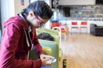 Teenage girl sitting in a cafe looking at her phone. 