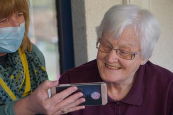 Woman holding a mobile phone for an elderly woman