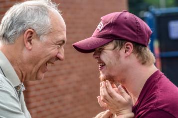 Young man with learning disabilities smiling at an older man