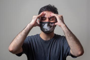 Person wearing face mask and holding head