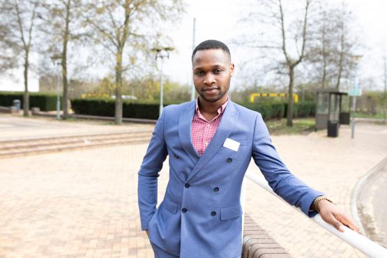 Man wearing a suit standing outside leaning on a hand rail