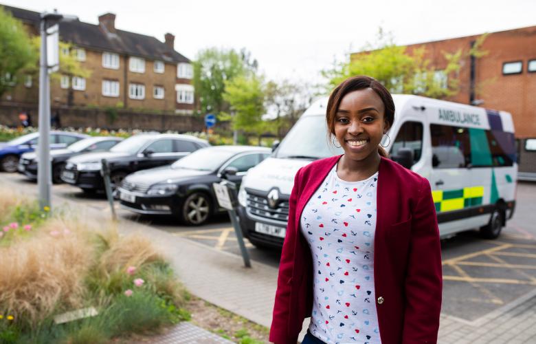 Woman standing outside a hospital in front of an ambulance